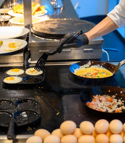 chef frying eggs in a restaurant kitchen