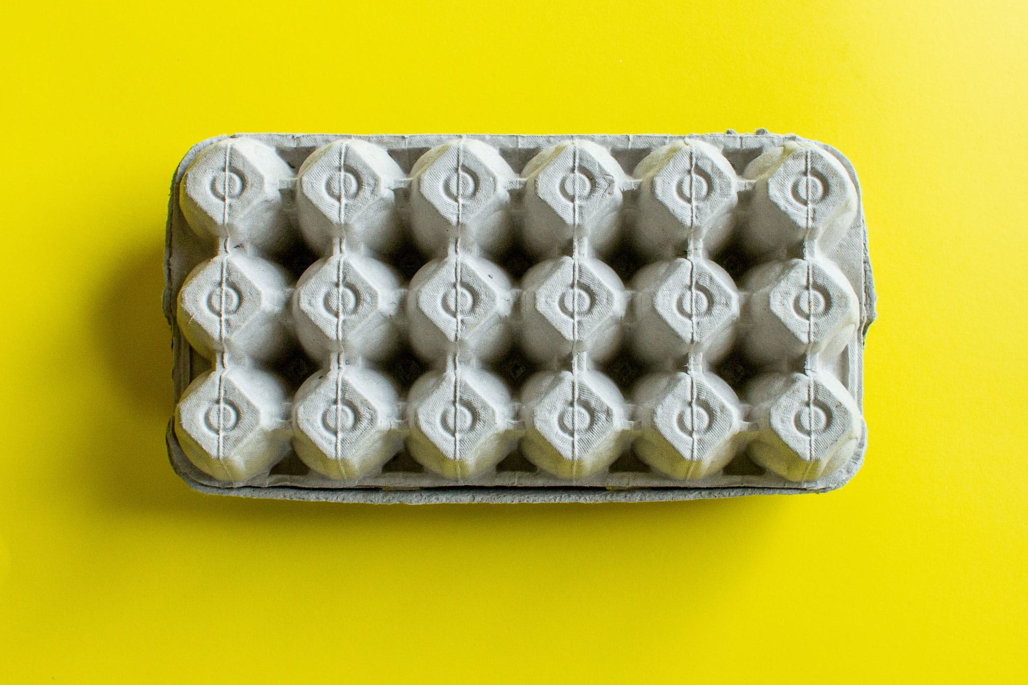 Image showcasing an 18-count package of white eggs yellow background , highlighting Eggs Unlimited's ability to offer safe packaging and delivery options in 18-egg configurations or any other requested sizes. The image serves to reassure customers of Eggs Unlimited's commitment to flexibility and care in meeting their specific egg packaging and shipping needs.
